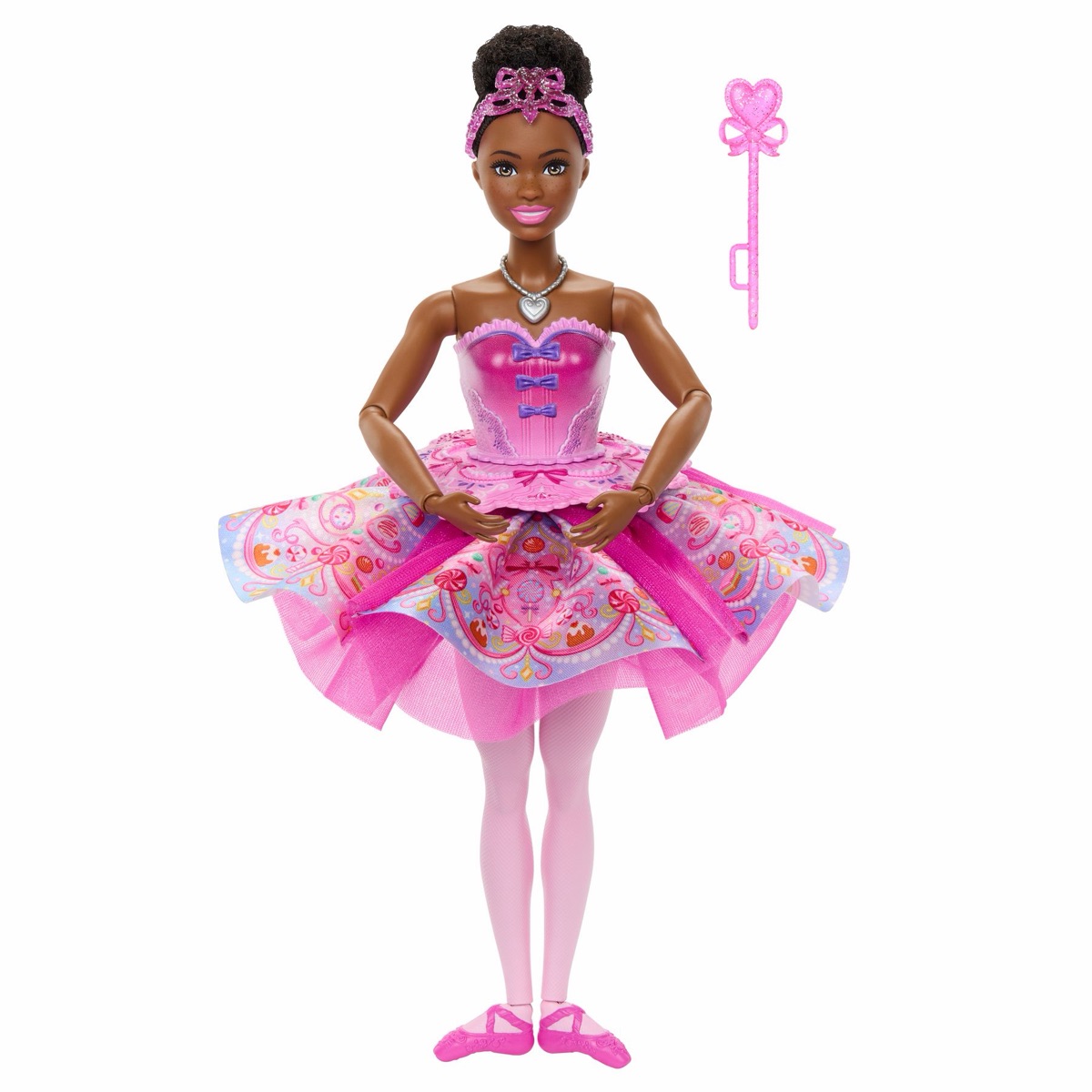 Mattel-Pressebild: Zuckerfee-Puppe JLW54 mit dunklem Haar, Diadem, rosa Ballettkleid mit Süßigkeiten-Muster und Herzmedaillon, daneben ein rosa Zauberstab