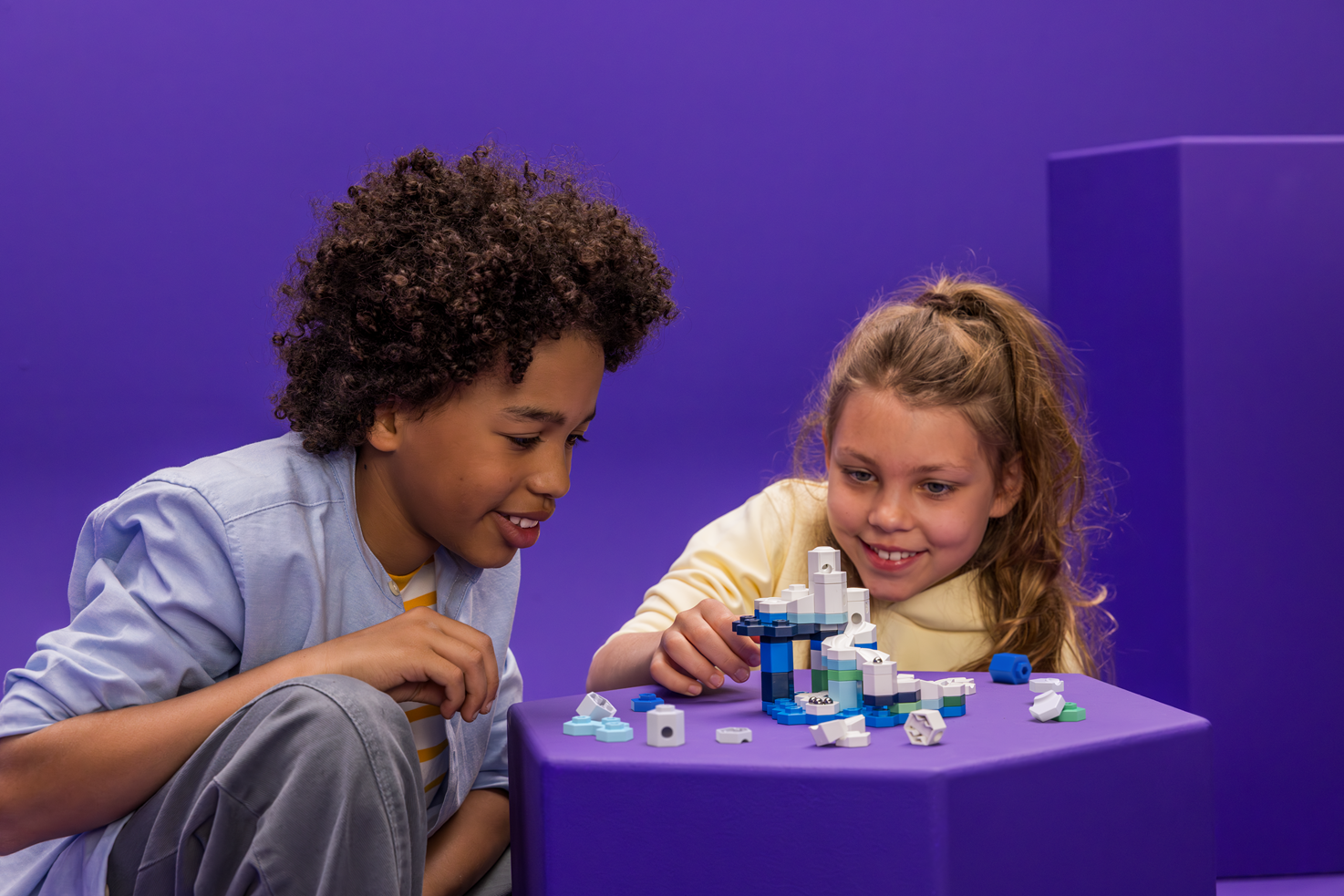 Zwei Kinder bauen auf einer kleinen Fläche eine blau-weiße GraviTrax-micro-Kugelbahn