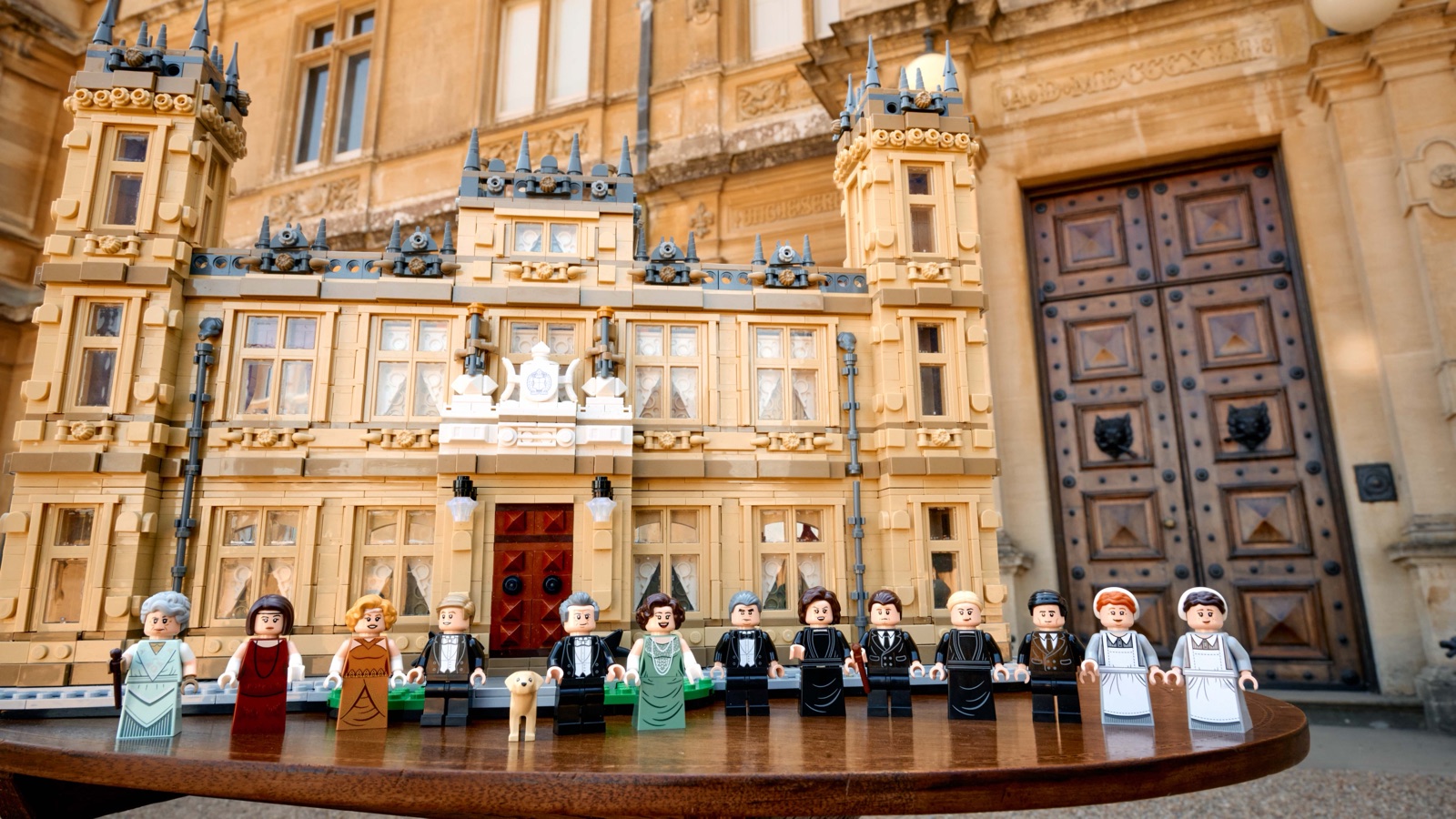 Die 13 Minifiguren des LEGO Downton Abbey Sets in einer Reihe vor dem Modell